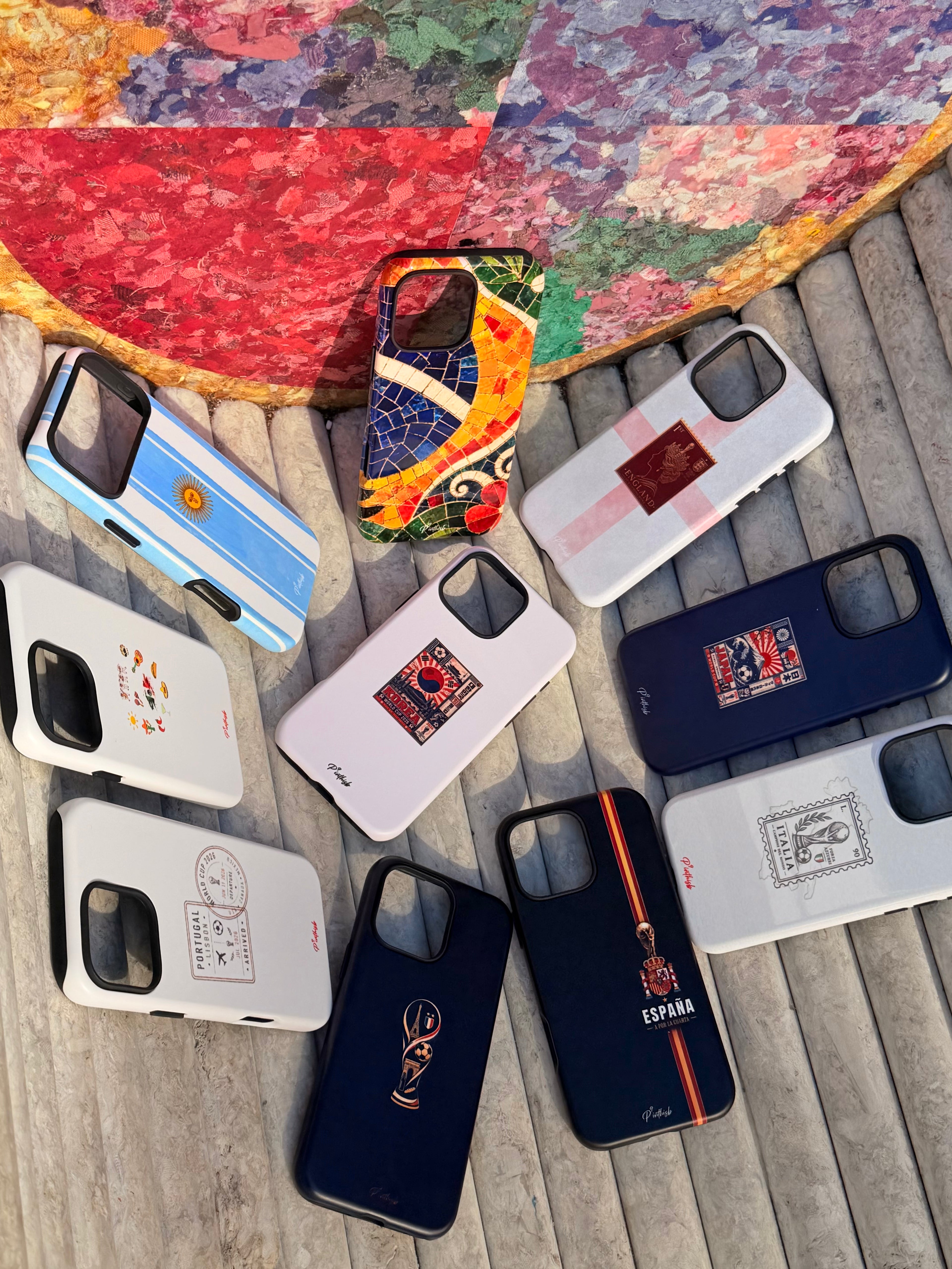 Collection of various phone cases on a wooden surface with a colorful mosaic background.