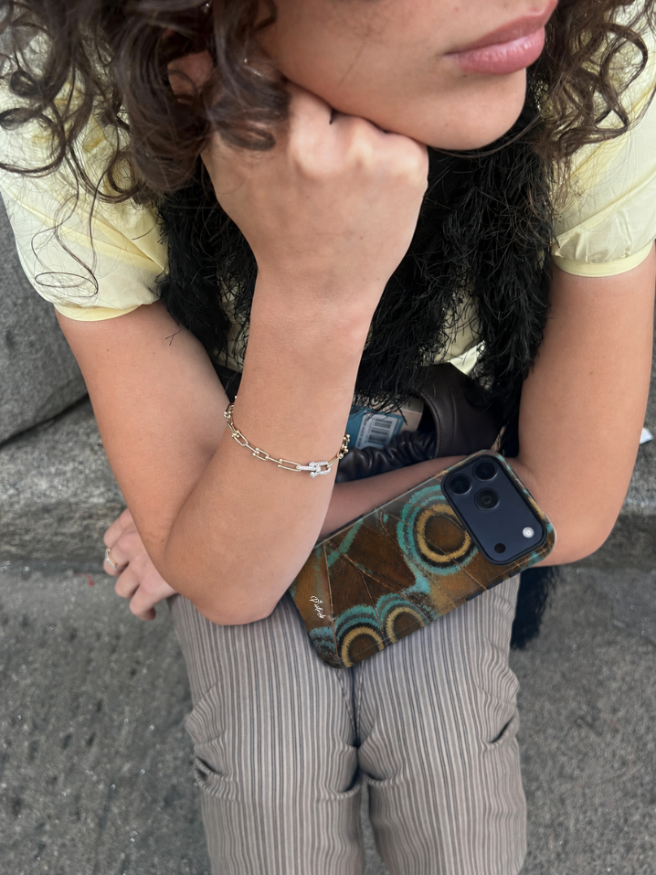 girl sitting on pavement looking away with a p9nthisb phone case on her lap
